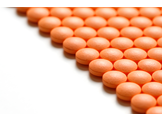 Rows of small orange pills on a white surface.